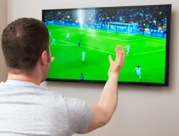 Мужчина смотрит футбол по телевизору дома . — стоковое фото