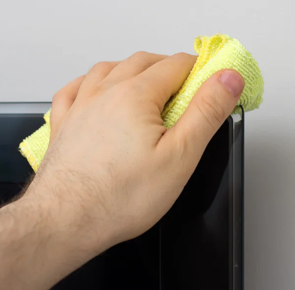 La mano del hombre limpia el polvo del panel de televisión . — Foto de Stock