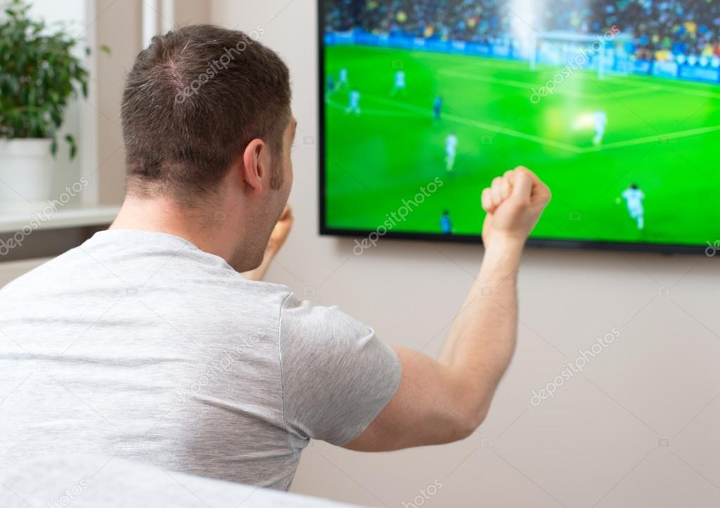 Goal! Man watching football match on television at home. Stock Photo by