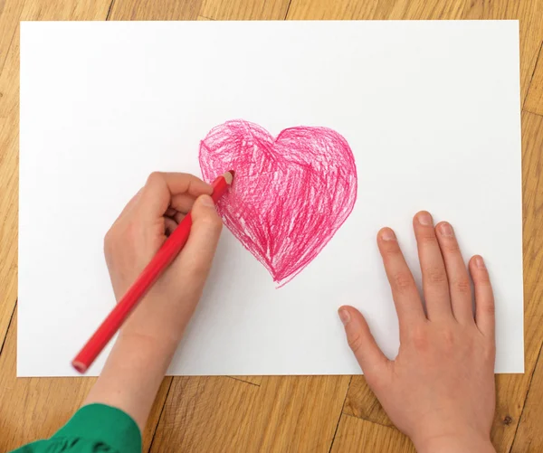 Child's hand drawing red heart on paper. — Stock Photo, Image