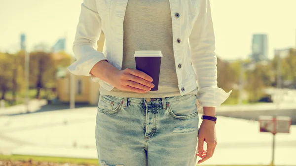 Les mains de la femme tenant une tasse de café dans la ville . — Photo