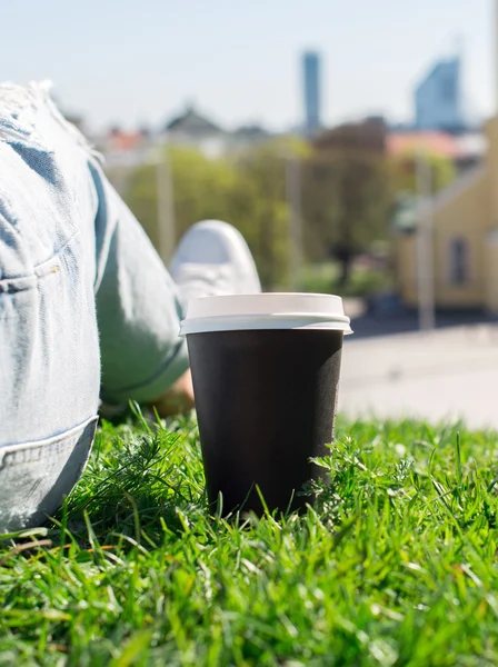 Femme reposant sur l'herbe avec une tasse de café . — Photo