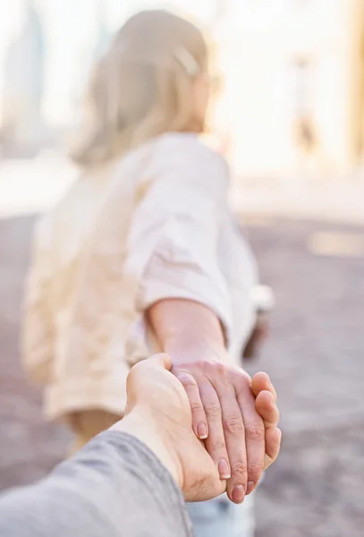 Woman holding man's hand and leads to the city. — Stock Photo, Image