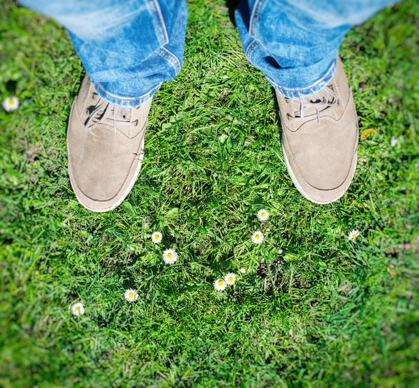 L'été arrive ! Bottes masculines sur l'herbe avec les premières fleurs. Vue du dessus . — Photo