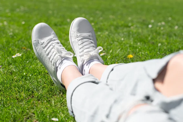 Ben i kvinnliga sneakers på gräset. — Stockfoto