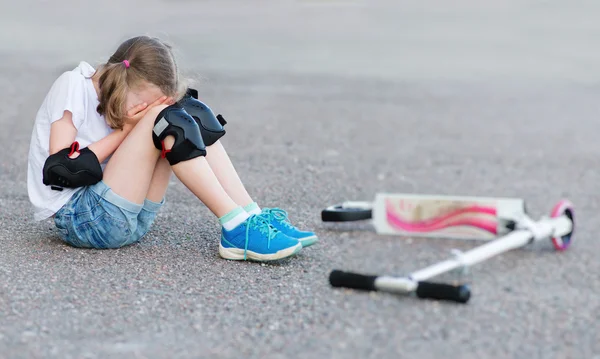 Маленькая девочка упала со скутера на улице. . — стоковое фото
