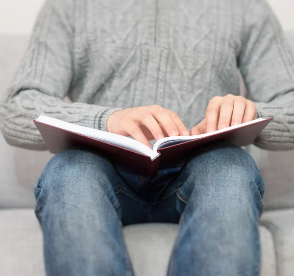 Hombre ciego leyendo el libro Braille en el sofá . — Foto de Stock