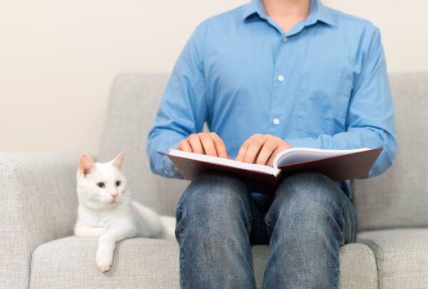 Blind man reading braille book on the couch.