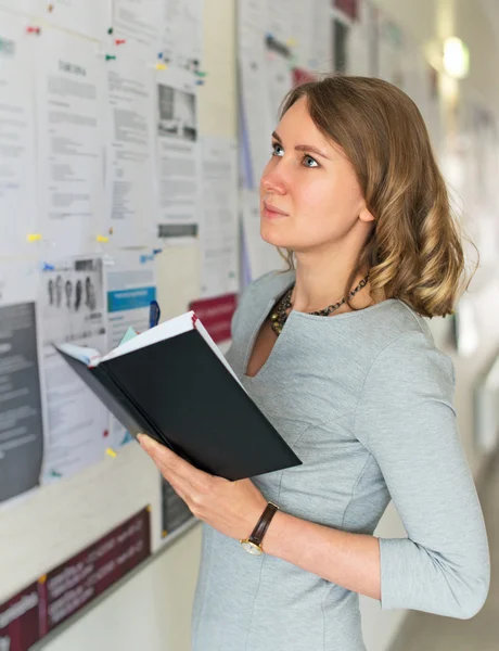 Jonge vrouwelijke student op zoek via werk biedt aan boord. — Stockfoto