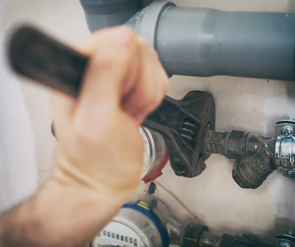 Male plumber fixing water meter with adjustable wrench. — Stock Photo, Image