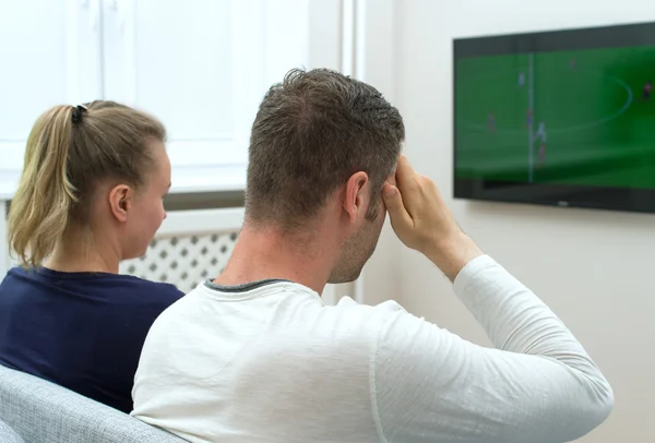 Triste casal assistindo jogo de futebol na televisão em casa . — Fotografia de Stock