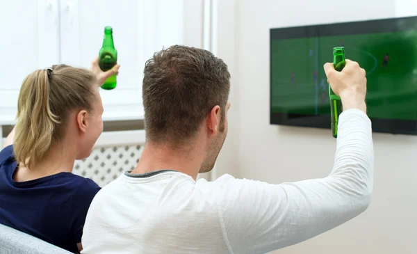 Aufgeregtes Paar schaut Fußballspiel im Fernsehen. — Stockfoto