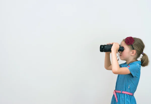 Little girl looking through binoculars. Space for your text. — Stock Photo, Image