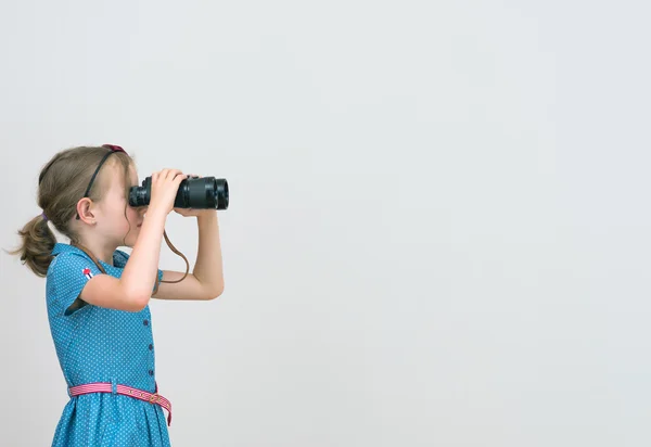 Little girl looking through binoculars. Space for your text. — Stock Photo, Image