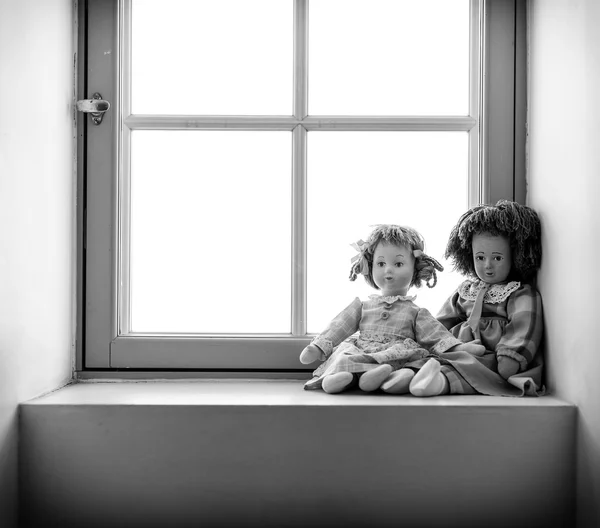 Two dolls near the window. Black and white photo. — Stock Photo, Image