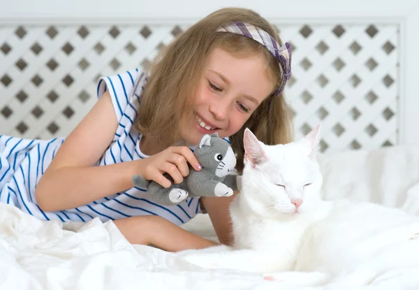 Malá dívka si hraje s kočkou v posteli. — Stock fotografie