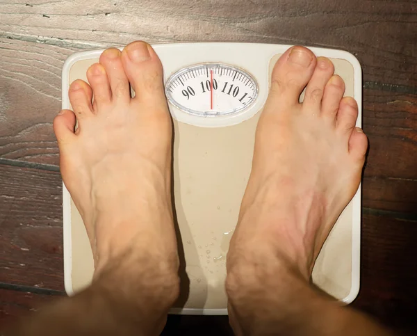 Uomo in piedi su bilance in bagno. Circa 100 kg . — Foto Stock