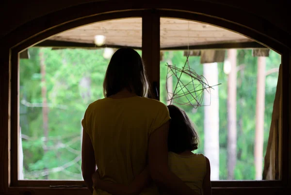 Mor och dotter tittar ut genom fönstret. — Stockfoto