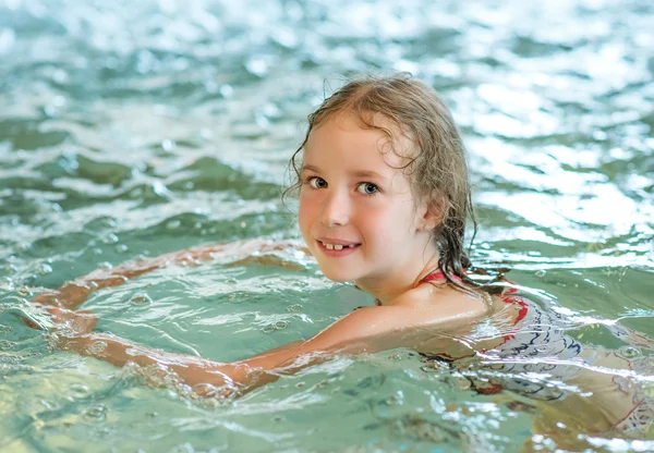 Kleines Mädchen schwimmt im Pool im Thermalbad. — Stockfoto