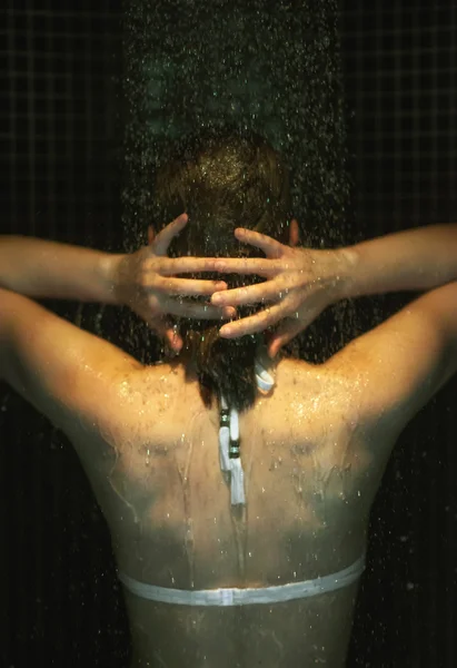 젊은 여자는 샤워를 즐기고. 후면 모습. — 스톡 사진