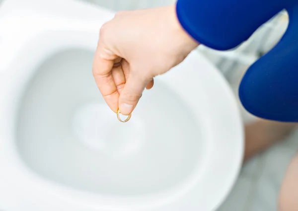 Echtscheiding-concept. Vrouw haar trouwring in het toilet gooien. — Stockfoto