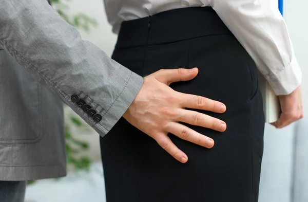 Assédio sexual no trabalho. Homem tocando bunda da mulher . — Fotografia de Stock