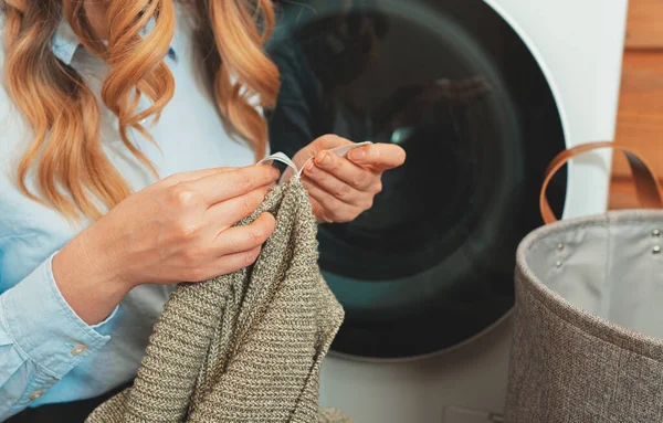 洗濯機に服をロードする前に服のタグを見て女性 — ストック写真