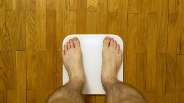 Bacakları terazide. Adam kilosunu kontrol ediyor..