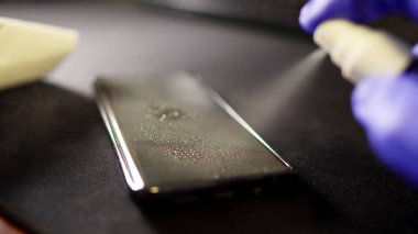Alkol spreyi ile temizlenmiş cep telefonlu koruyucu eldiven verin. Covid-19 dezenfeksiyon konsepti.