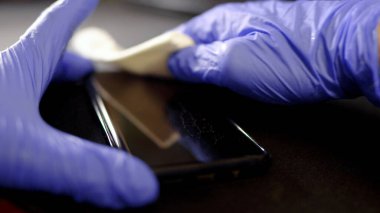 Koruyucu eldiven ve peçete temizleme cep telefonu. Covid-19 dezenfeksiyon konsepti.