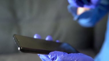 Alkol spreyi ile temizlenmiş cep telefonlu koruyucu eldiven verin. Covid-19 dezenfeksiyon konsepti.
