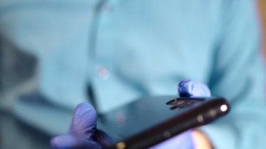 Alkol spreyi ile temizlenmiş cep telefonlu koruyucu eldiven verin. Covid-19 dezenfeksiyon konsepti.