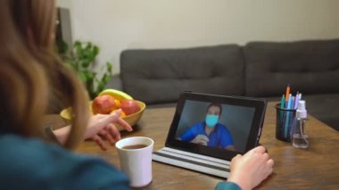 Çay içen ve doktoruyla görüntülü konuşma yapan bir kadın..