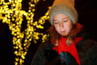 Geceleri sokakta akıllı telefonları olan bir kız..