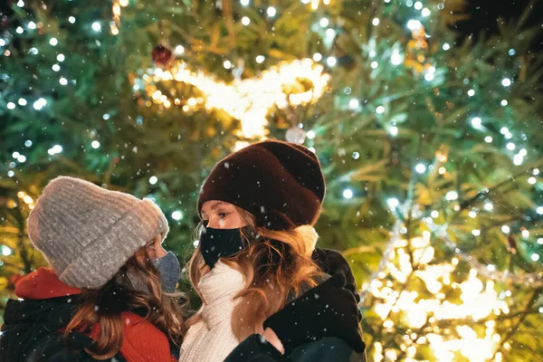 Anne ve kızı, Noel ağacının yanında koruyucu maskeler takmış..