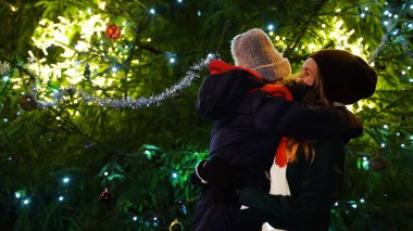 Anne ve kızı, Noel ağacının yanında koruyucu maskeler takmış..