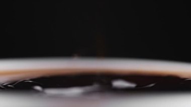 Beyaz fincana düşen kahve damlası. Yavaş çekim.