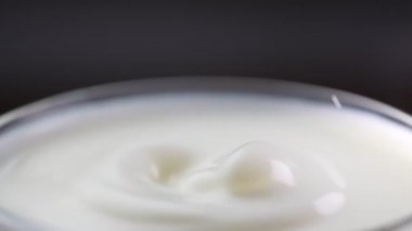 Süt damlası dolu bardağa düşer. Yavaş çekim.