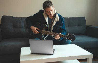 Öğretmen gitar çalmayı gösteriyor. Uzak çevrimiçi ders.