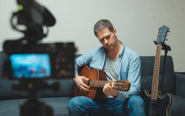 Video kameranın önünde İspanyol gitarlı bir adam..