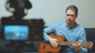 Video kameranın önünde İspanyol gitarlı bir adam..