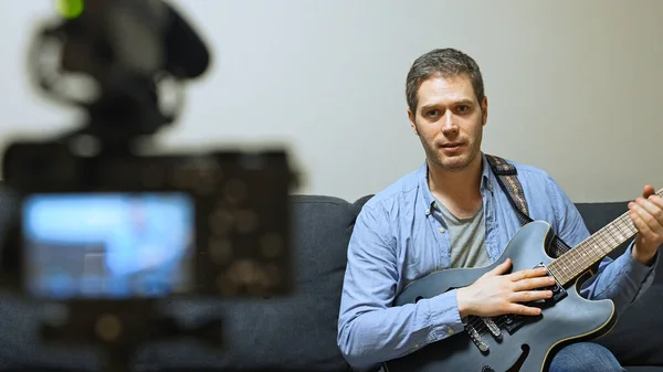 ビデオカメラの前で半音響ギターを持つ男 — ストック写真