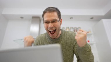 Dizüstü bilgisayarın önündeki heyecanlı adam. Çevrimiçi oyun kavramı.