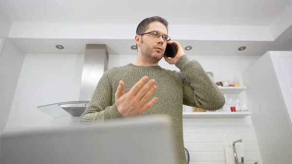 動揺してる男が携帯電話で話してる 家から仕事をする — ストック写真