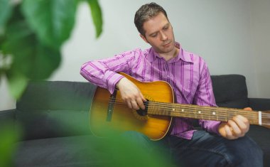 Evde naylon gitar çalan yakışıklı adam..