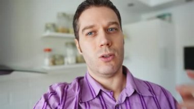 Gülümseyen yakışıklı adam evinden video blogu kaydediyor..