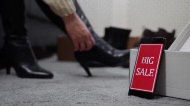 Kadın büyük bir satışta ayakkabı deniyor..