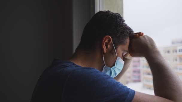Tıbbi Maskeli Yorgun Adam Pencereden Dışarı Bakıyor — Stok video