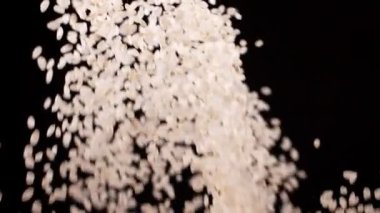 Ağır çekimde siyah arkaplanda pirinç patlaması.