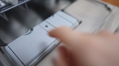 Bulaşık makinesine deterjan koyan adam..